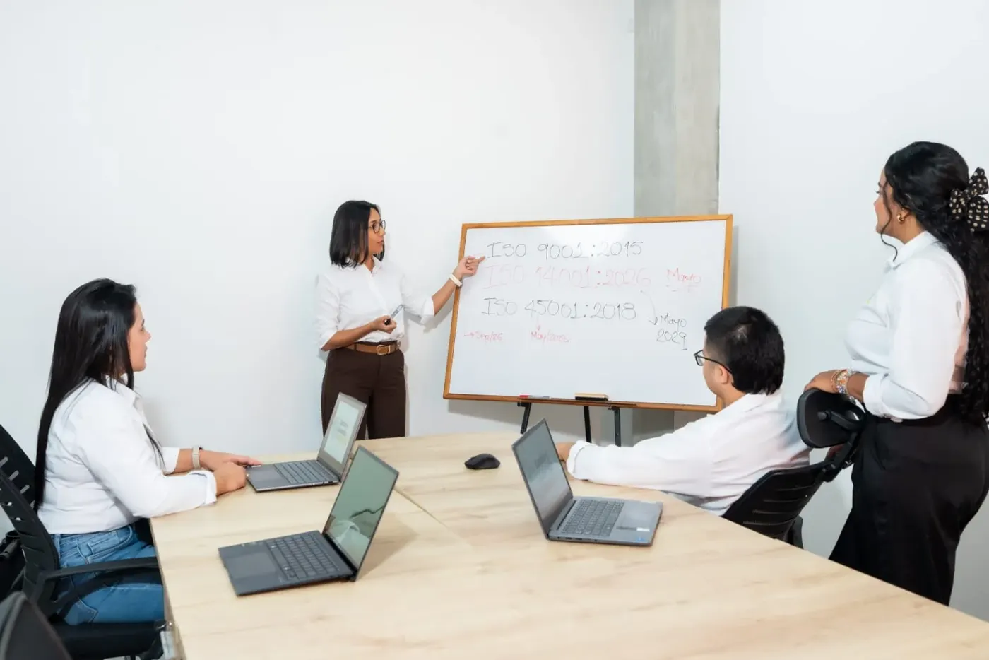 Consultora de GDE explicando las normas ISO 9001, 14001 y 45001 a un equipo de trabajo